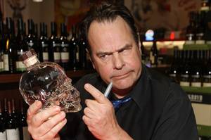 Dan Aykroyd cautiously stares at a bottle of his Crystal Head Vodka.