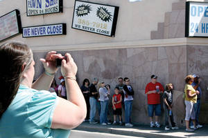 Visitors cross Las Vegas Blvd. to take pictures of friends and family waiting in line at Gold &amp; Silver Pawn.
