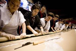 Student sushi cooks help assemble a 40-foot sushi roll at Taste of UMass. 