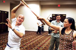 Nick Gallard, left, the sword master and stunt ccordinator for Star Wars I-III helps out Cami Lutgens of Blacksburg, Va. during the Jedi Fighting Masterclass at Combatcon in the Tuscany Casino in Las Vegas Friday, June 24, 2011.
