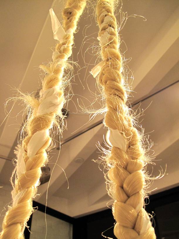 Synthetic hair, braided with strips of fabric containing people's dreams, hangs from the ceiling inside P3 Studio. The braids are woven into artist MK Guth's own hair. 