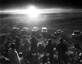 In this June 24,1957 photo from the Las Vegas News Bureau, photographers are seen lined up to shoot the above ground detonation of a bomb at the Nevada test site.