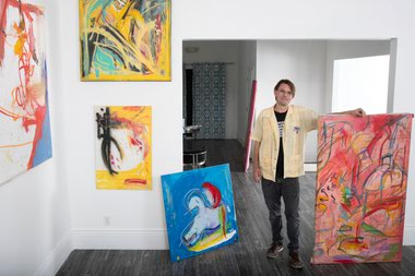 Artist Brian C. Gibson poses with his artwork as he sets up for his Boytoy Summer show at Inside Style on Main Street.