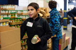 A young volunteer packs boxes with groceries