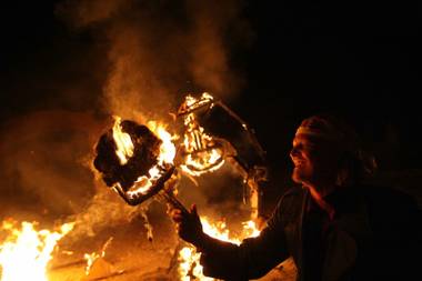 Sam Gurr, the creator of the three monster effigies, holds a flaming head aloft.