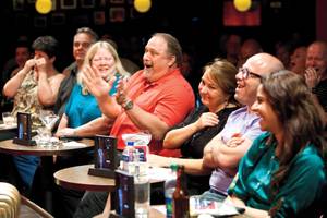 Audience members crack up laughing as comedians heckle front-row guests at Brad Garrett’s Comedy Club.