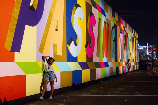 A festival attendee poses in front of Lakwena’s “JUST PASSING THROUGH” mural.