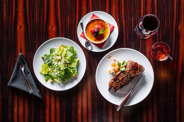 Creme brulee, New York steak with grilled jumbo shrimp and a Caesar salad from the Charcoal Room’s happy hour prix fixe menu
