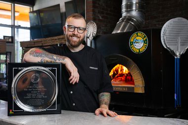 Yukon Pizza co-owner Alex White displays his International Pizza Expo World Champion title for Best Non-Traditional Pizza. 