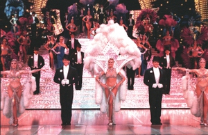 In Jubilee at Bally’s in 2000, the center performer wears a backpack, a steel-framed accessory that surrounds the showgirl and amplifies her silhouette.