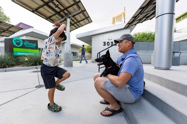 A child and Simon Yue, right, meet with a one-year-old mix breed dog named Morticia at the Animal Foundation on October&nbsp;14. 