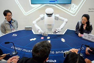People watch as the Sharpa North robot deals poker at the Sharpa booth during the CES tech show Wednesday, Jan. 7, 2026, in Las Vegas. (AP Photo/John Locher)