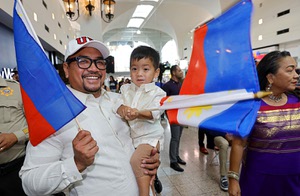 Jab Buhay and his son Sebastian, 2, wave flags of the Philippines during a community celebration at Boulevard Mall to commemorate the new Filipino Town, October 9, 2025. 