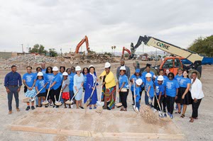 Students and staff shovel dirt during a groundbreaking ceremony. 
